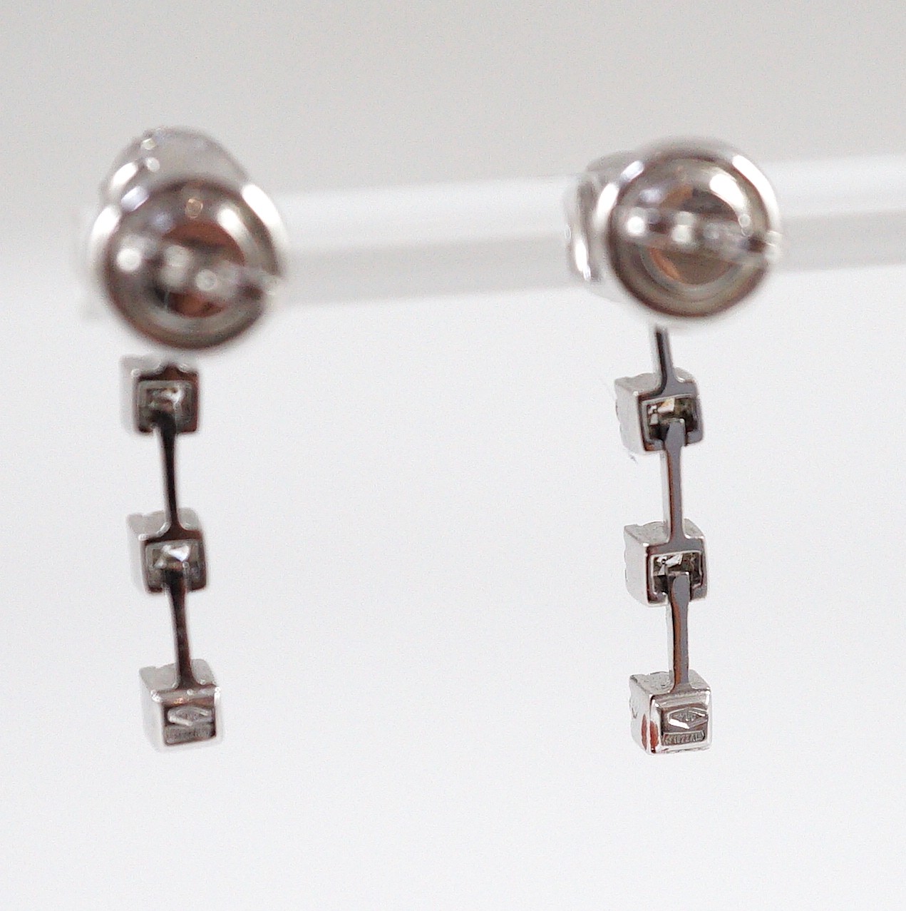 A modern pair of 18ct white gold, diamond cluster and three stone diamond drop set earrings
